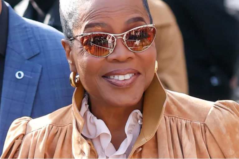 Oprah Winfrey at Paris Fashion Week Chloe Show wearing GIMME Tigga Tube Hoops, sunglasses and a peach, suede jacket.